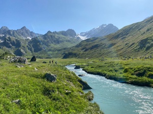 Hiking over a stream in the French Alps in summer.