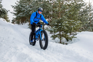 Man fat biking through forest.