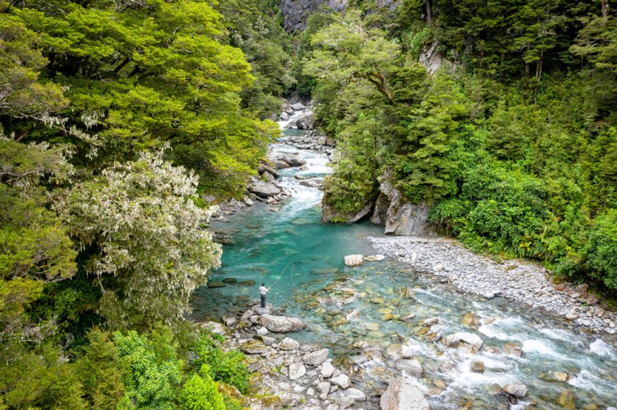 A person fly fishing in a rocky river.
