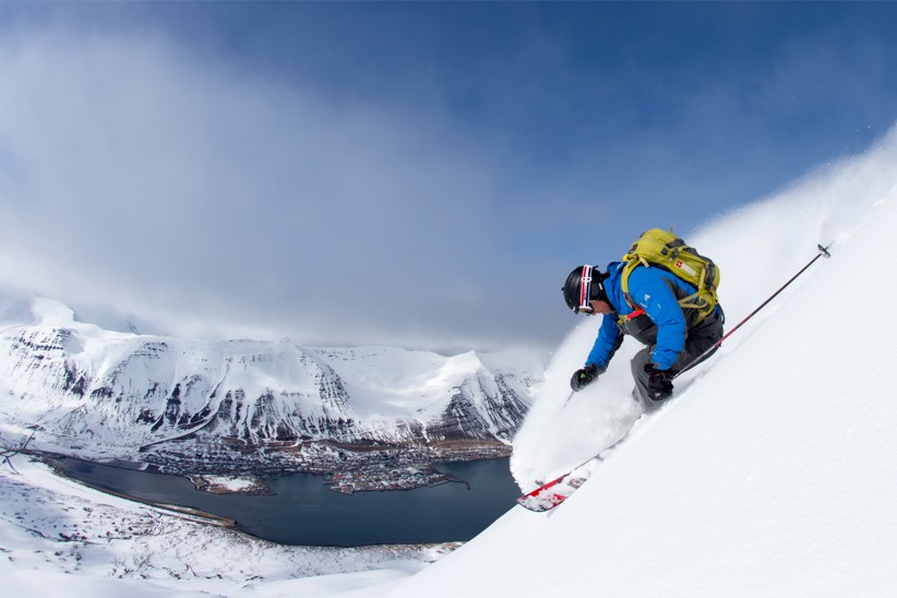 A person skiing downhill with a large lake in the background.