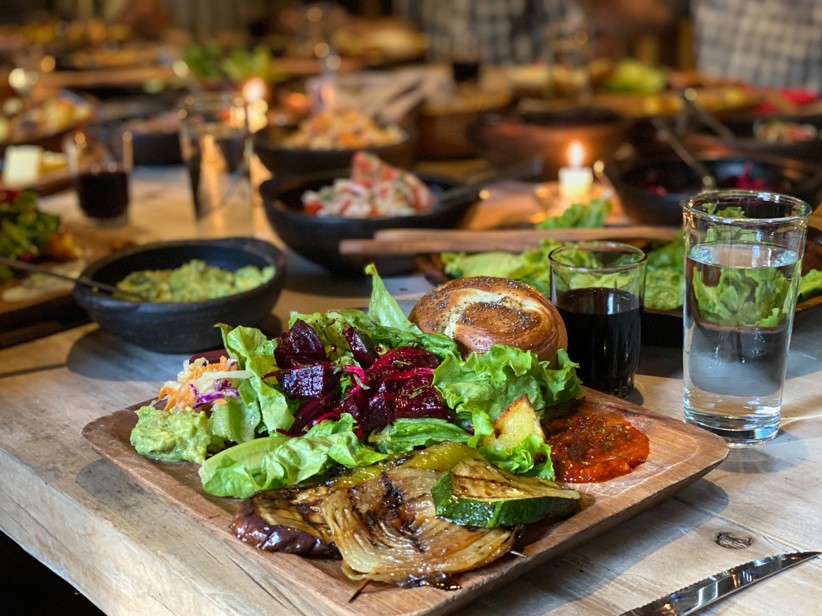 A large feast with fresh vegetables, guacamole, and bread.