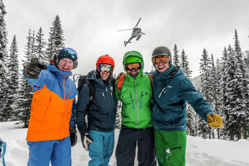 A group of people taking a photo together with a helicopter passing overhead.