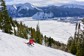 A skier going down a mountain with a view of a French town in the distance.
