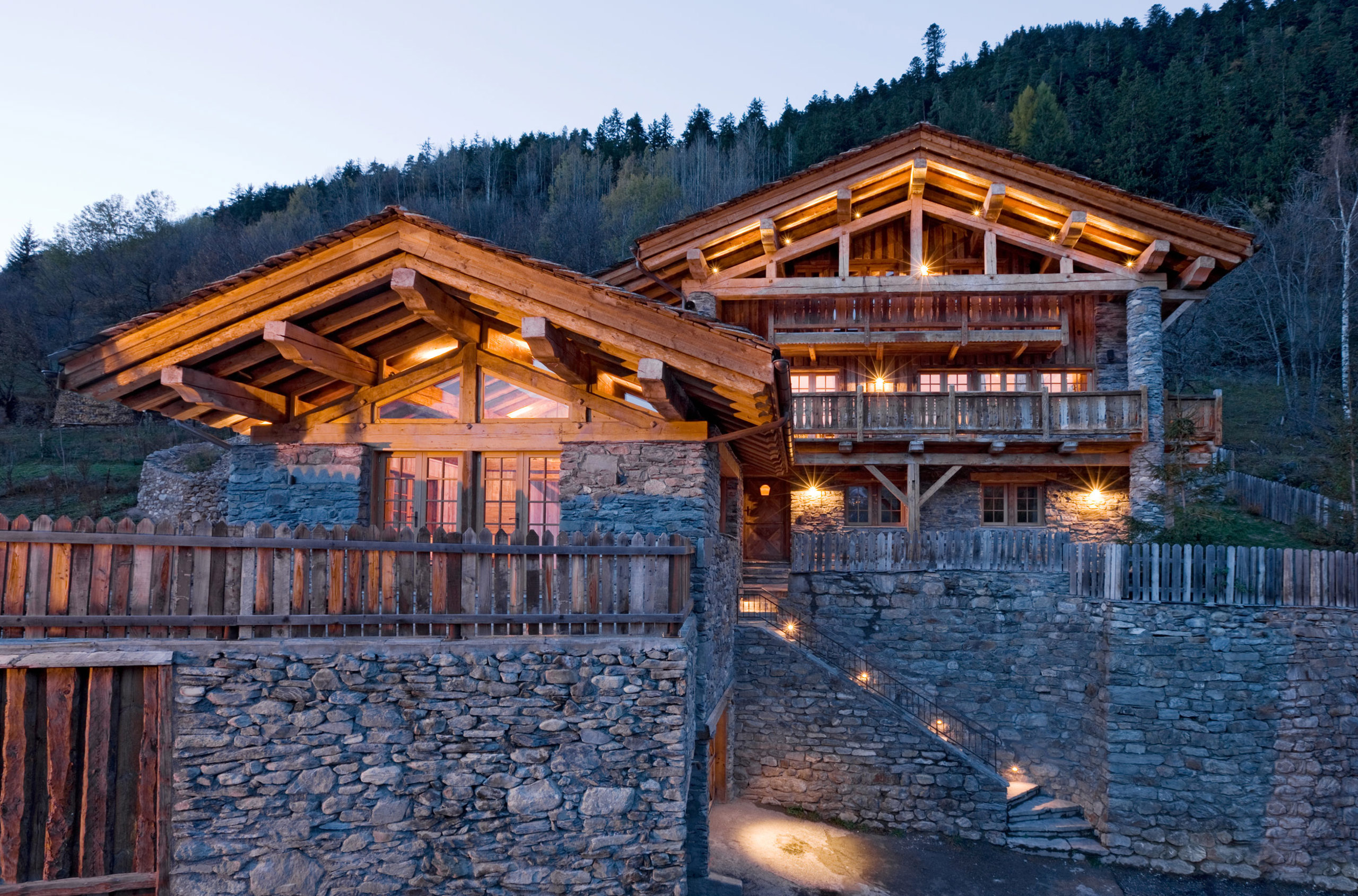 exterior of a classic french chalet on a summer night, with a warm glow coming from the windows.