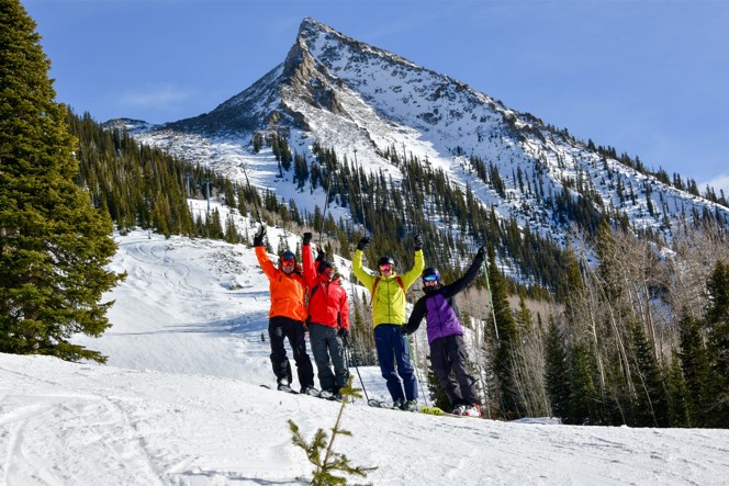 A group of friends celebrating half way down a ski mountain.