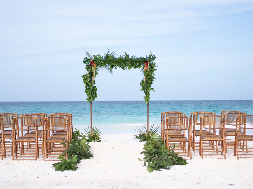 Chairs and arch are set-up on a beach for a wedding.