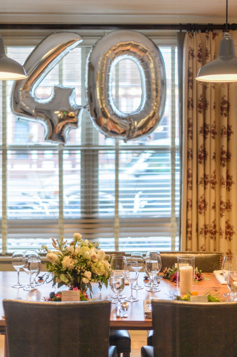 A birthday meal set up with a flower bouquet on the table and balloons.