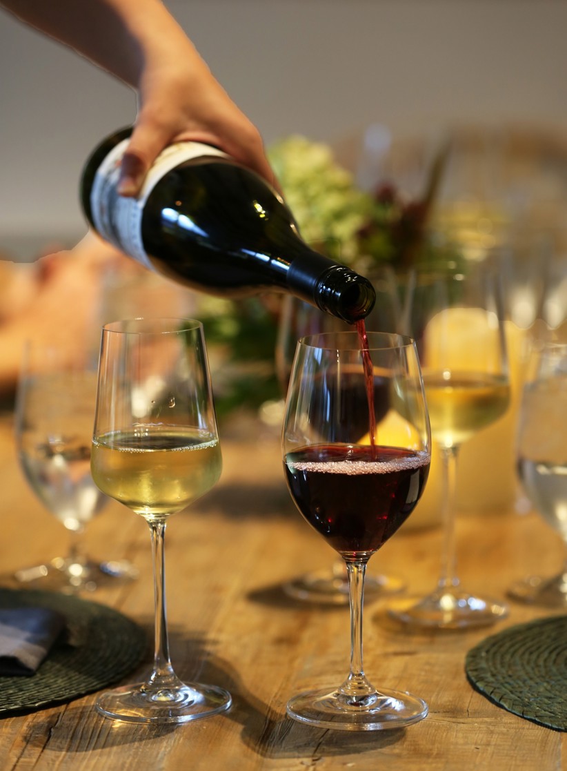 Various glasses of white and red wine being poured.