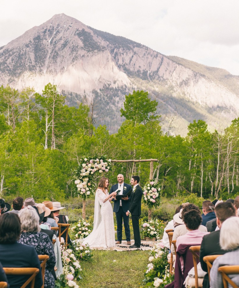 A soon-to-be husband and wife exchanging vows at their wedding ceremony and a mountain in in the dis