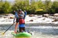A guide and a child learning how to ride a stand up paddle board.